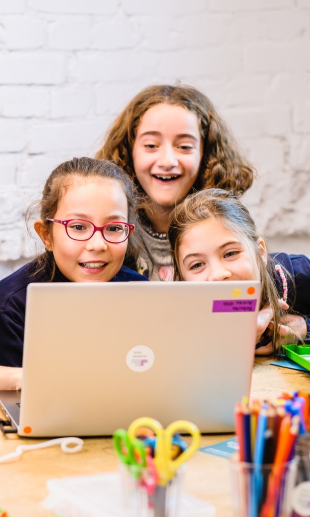 3 Mädchen schauen begeistert in einen Laptop.